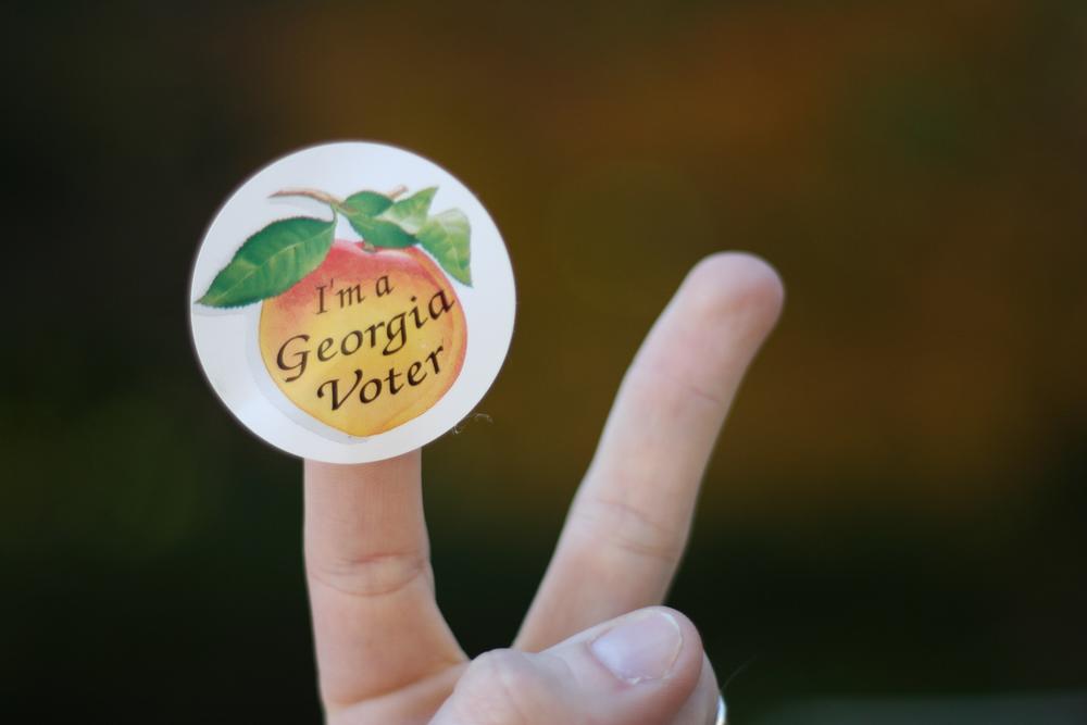 Finger with a Georgia voter sticker on them